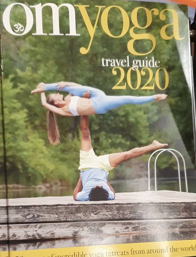 OM Yoga Travel Guide 2020 cover featuring Pip in an acroyoga pose on a lakeside jetty