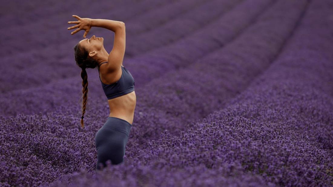 Pip arching back with her arm raised in a lavender field